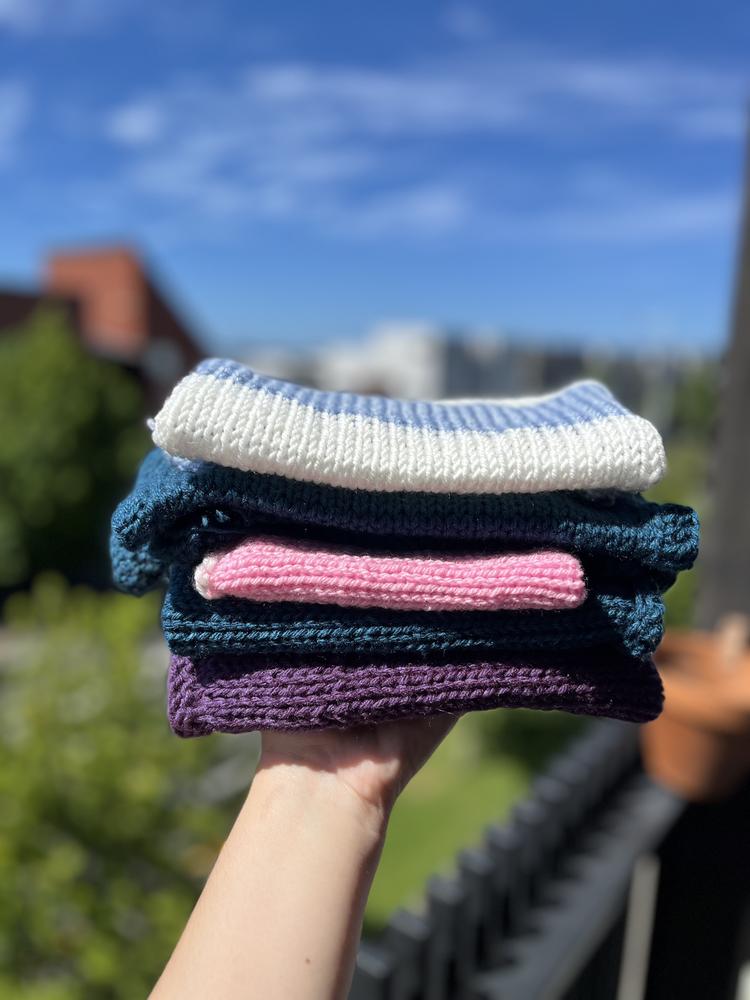 A hand holds up a pile of blankets on a sunny day.